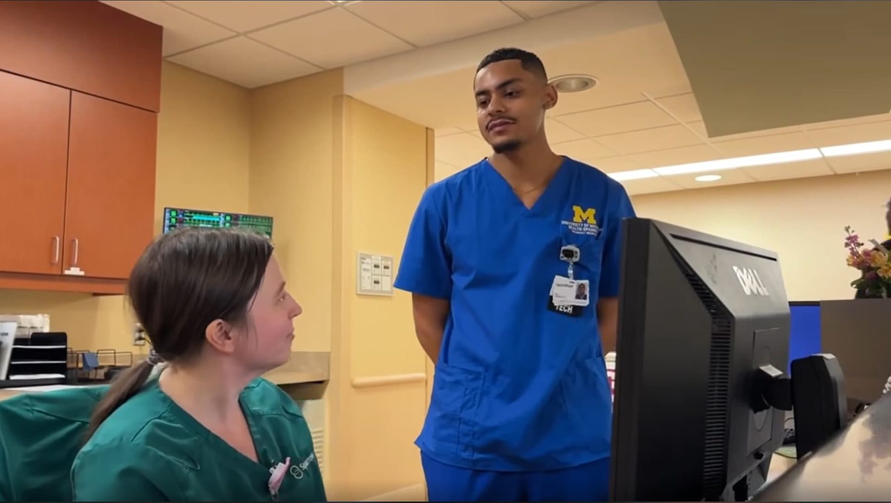 two nurses in scrubs, a woman and a man, in discussion